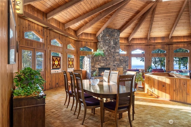 dining area with wooden walls, a fireplace, lofted ceiling with beams, light carpet, and wooden ceiling