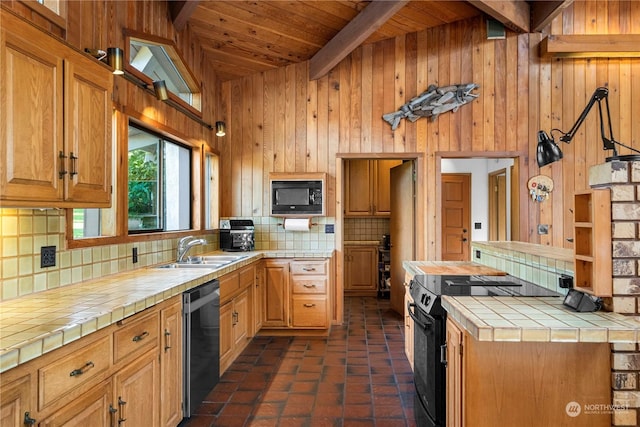 kitchen featuring sink, tile countertops, black appliances, wooden walls, and backsplash