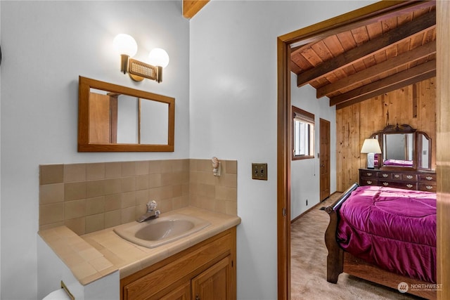 bathroom with lofted ceiling with beams, wooden ceiling, vanity, wooden walls, and backsplash