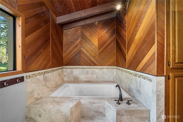 bathroom featuring tiled tub, a healthy amount of sunlight, and wood walls