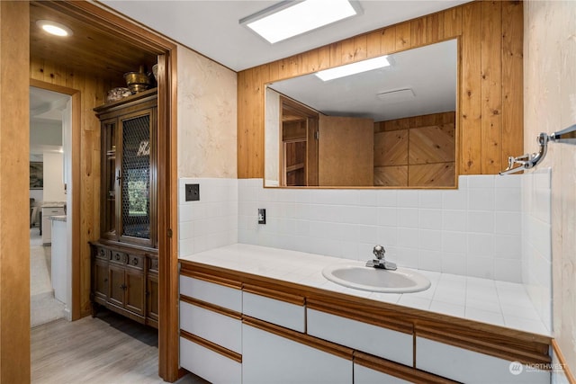 bathroom featuring tasteful backsplash, vanity, hardwood / wood-style floors, and wooden walls