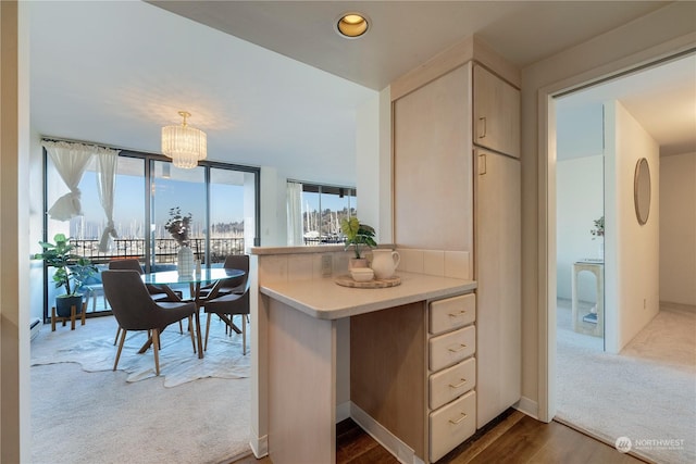 kitchen featuring decorative light fixtures, carpet flooring, a chandelier, and kitchen peninsula