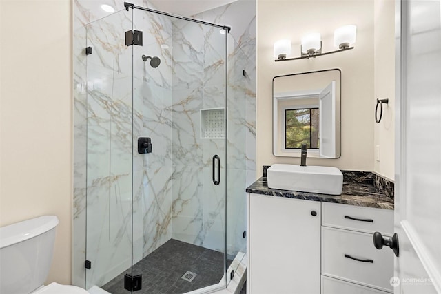 bathroom featuring vanity, a shower with door, and toilet