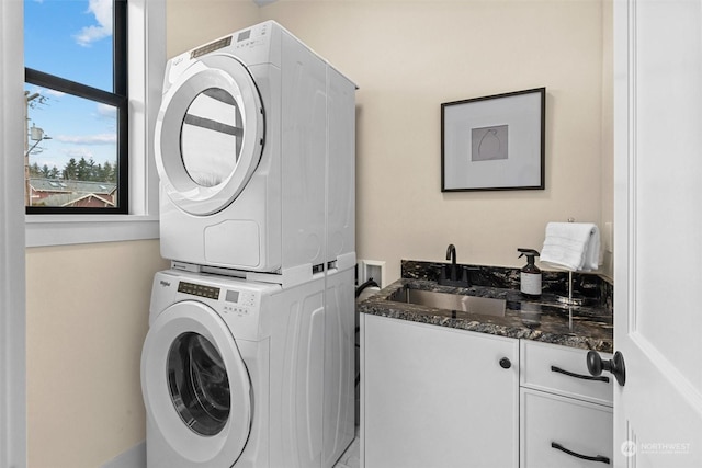 washroom featuring sink, cabinets, and stacked washing maching and dryer