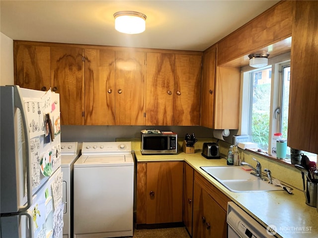 kitchen with light countertops, white appliances, washer and clothes dryer, and brown cabinetry