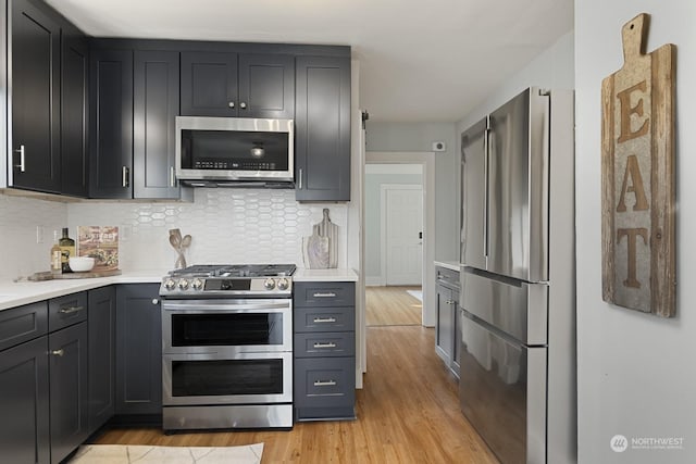 kitchen featuring stainless steel appliances, light hardwood / wood-style floors, and backsplash