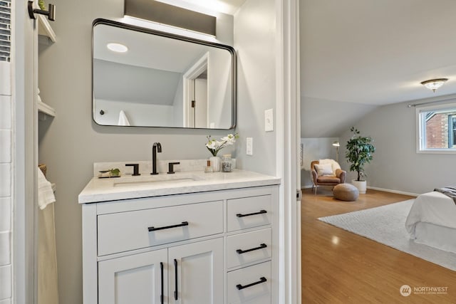 bathroom with vanity, hardwood / wood-style floors, and vaulted ceiling