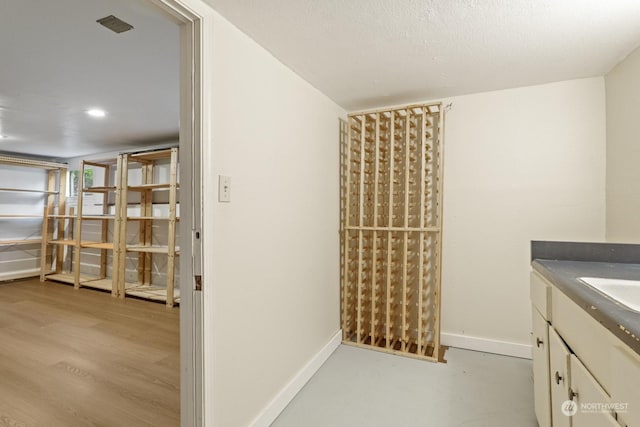 wine area with a textured ceiling and light wood-type flooring