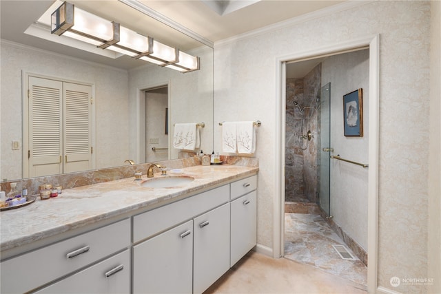 bathroom with vanity, ornamental molding, and tiled shower