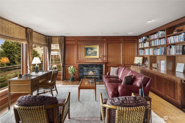 living area with wooden walls, a premium fireplace, and light wood-type flooring