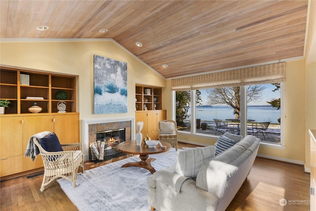 living room with lofted ceiling, a water view, wood ceiling, light wood-type flooring, and a tile fireplace