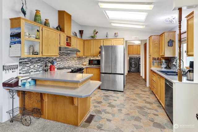 kitchen featuring sink, vaulted ceiling, a kitchen breakfast bar, stainless steel fridge, and kitchen peninsula