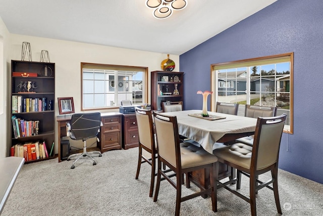 dining space with lofted ceiling and light colored carpet