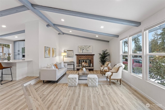 living room featuring light hardwood / wood-style flooring, a brick fireplace, and vaulted ceiling with beams