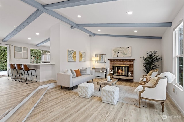 living room featuring a brick fireplace, vaulted ceiling with beams, and light hardwood / wood-style floors