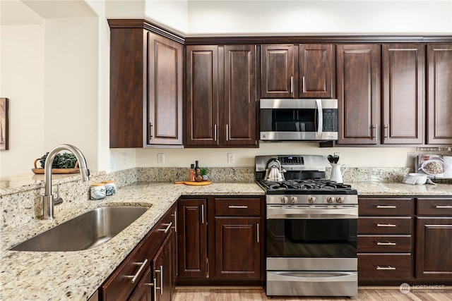 kitchen with sink, light hardwood / wood-style flooring, dark brown cabinets, stainless steel appliances, and light stone counters