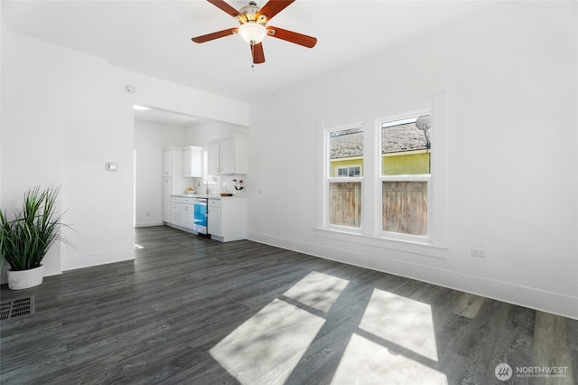 unfurnished living room with visible vents, dark wood-type flooring, a ceiling fan, a sink, and baseboards