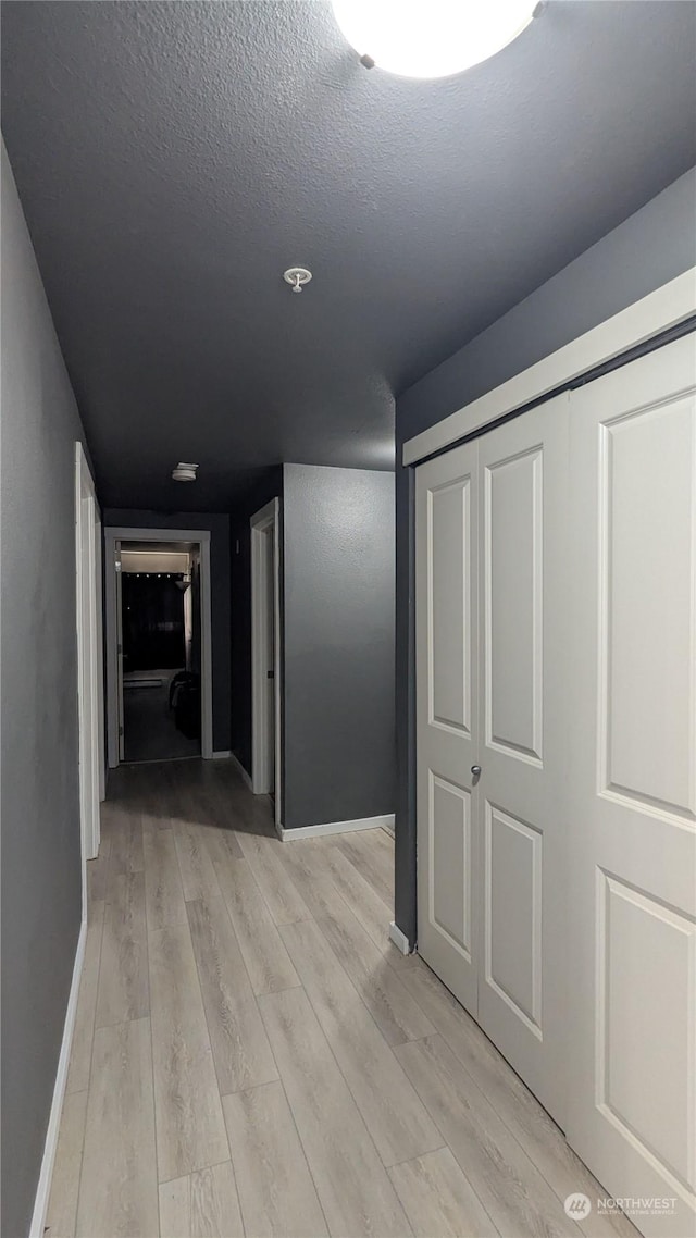 hall with light hardwood / wood-style flooring and a textured ceiling