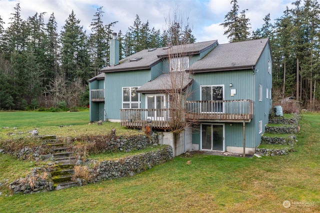 rear view of property featuring a wooden deck and a lawn