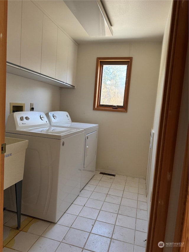 laundry room with washer and clothes dryer, cabinets, and light tile patterned flooring