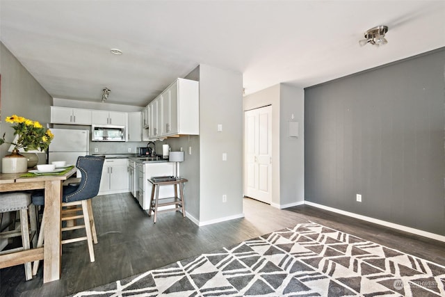 kitchen with white cabinetry, sink, dark wood-type flooring, and white fridge