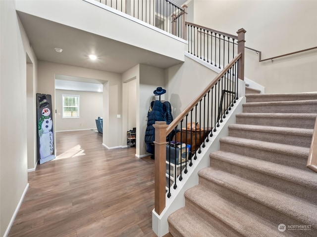 stairway featuring a towering ceiling and wood-type flooring