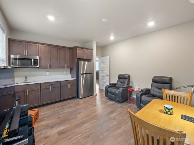 kitchen featuring dark brown cabinetry, sink, stainless steel appliances, and light hardwood / wood-style floors