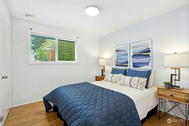 bedroom with hardwood / wood-style floors and a textured ceiling