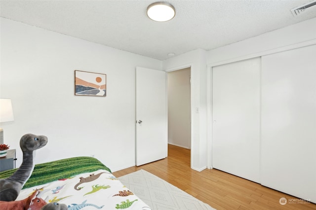 bedroom with hardwood / wood-style flooring, a closet, and a textured ceiling