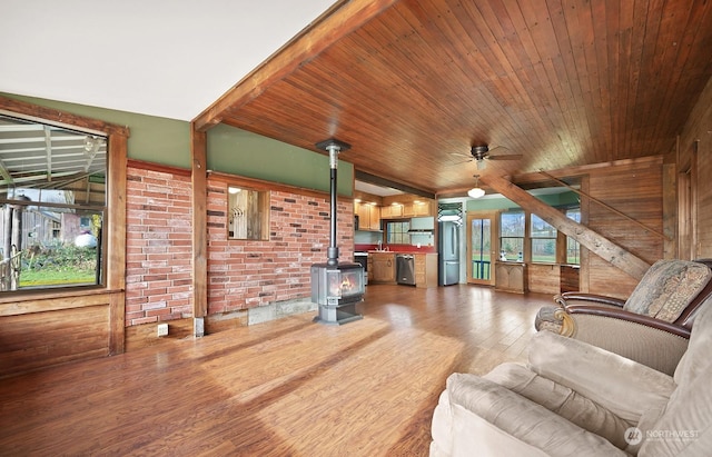 unfurnished living room with a wood stove, sink, hardwood / wood-style flooring, ceiling fan, and wood ceiling