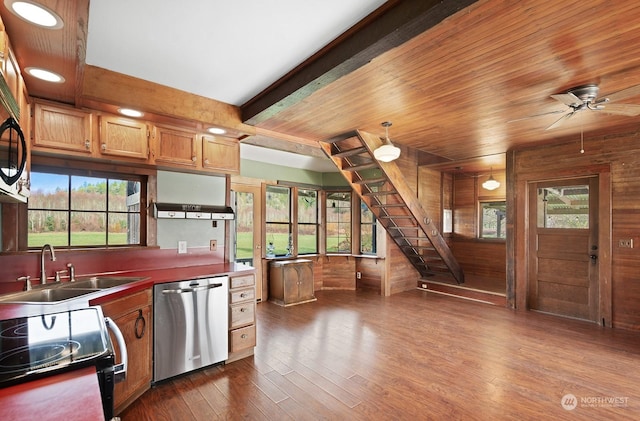 kitchen with dark wood-type flooring, sink, wood walls, dishwasher, and beamed ceiling