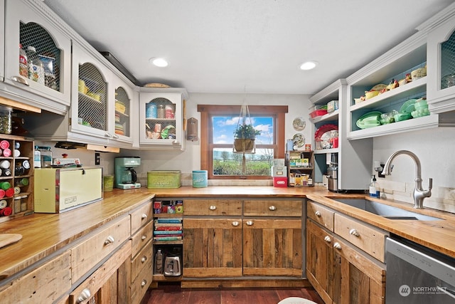 kitchen with sink, butcher block countertops, white cabinetry, dark hardwood / wood-style flooring, and dishwasher