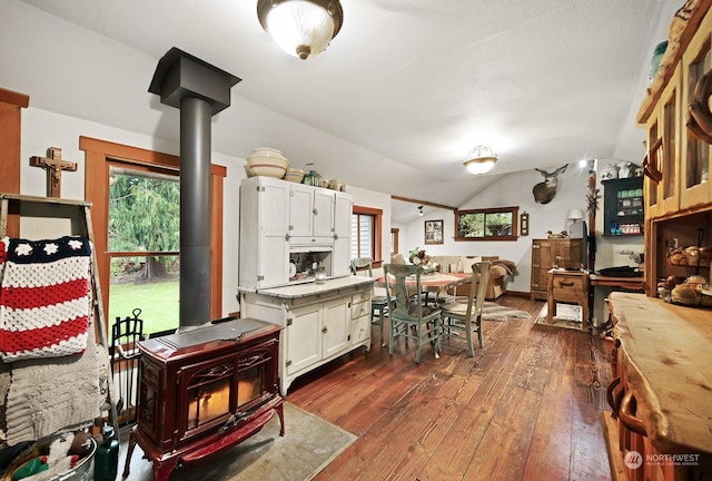 kitchen featuring white cabinetry, dark hardwood / wood-style flooring, vaulted ceiling, and a wood stove