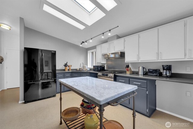 kitchen featuring vaulted ceiling with skylight, white cabinetry, under cabinet range hood, and black appliances