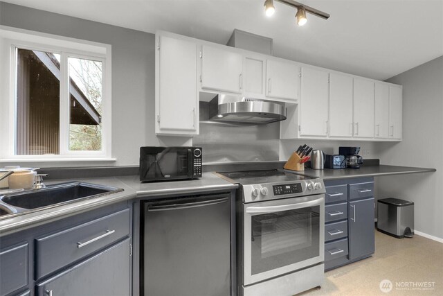 kitchen with wall chimney exhaust hood, stainless steel appliances, white cabinetry, a sink, and baseboards