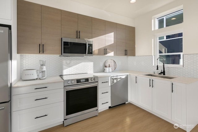 kitchen with white cabinetry, sink, stainless steel appliances, and light hardwood / wood-style floors