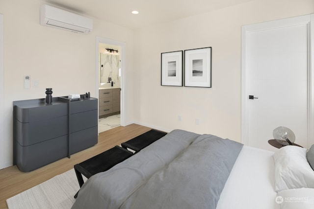 bedroom featuring ensuite bathroom, a wall mounted air conditioner, and light hardwood / wood-style floors