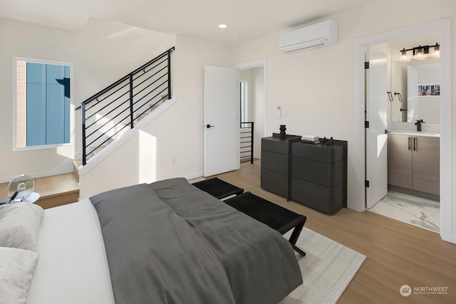 bedroom with sink, light hardwood / wood-style flooring, and an AC wall unit