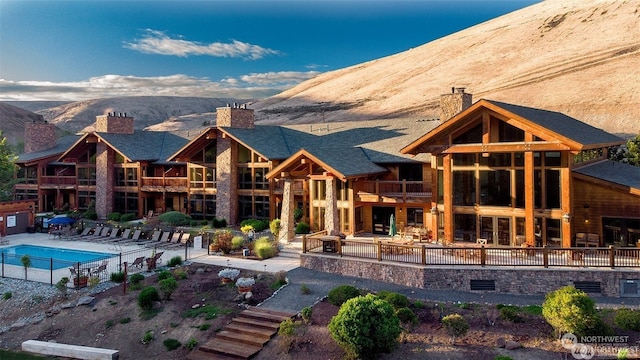 back of property featuring a patio, a mountain view, and a community pool