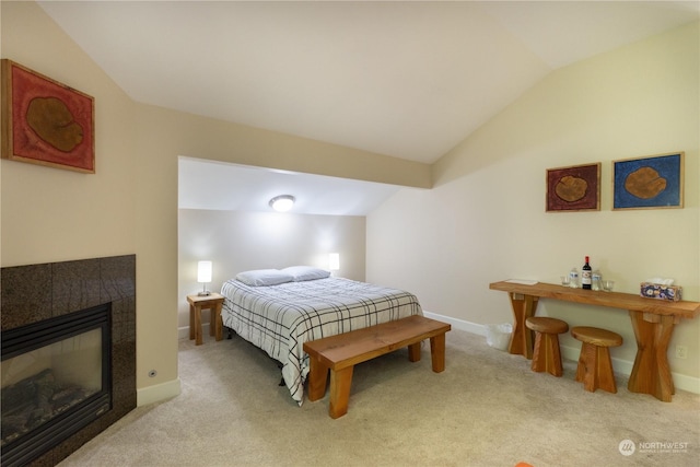 carpeted bedroom with vaulted ceiling and a fireplace