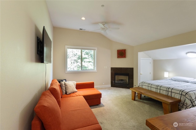 carpeted bedroom featuring lofted ceiling, a tiled fireplace, and ceiling fan