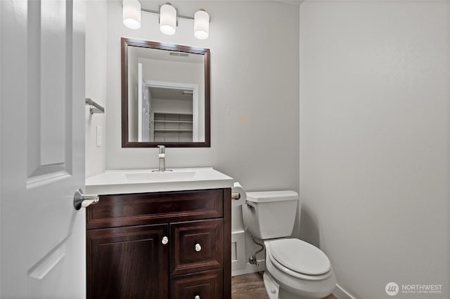 bathroom featuring baseboards, vanity, toilet, and wood finished floors