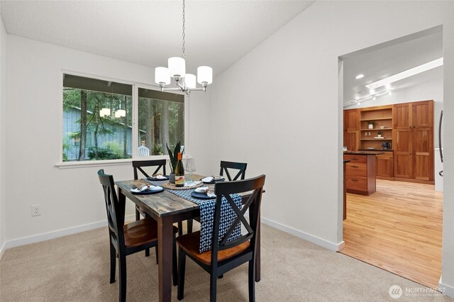 dining space with baseboards, an inviting chandelier, and light colored carpet