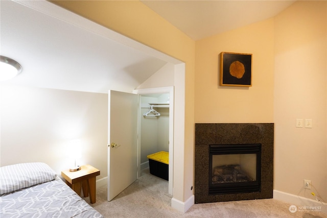 bedroom featuring lofted ceiling, a fireplace, and light carpet