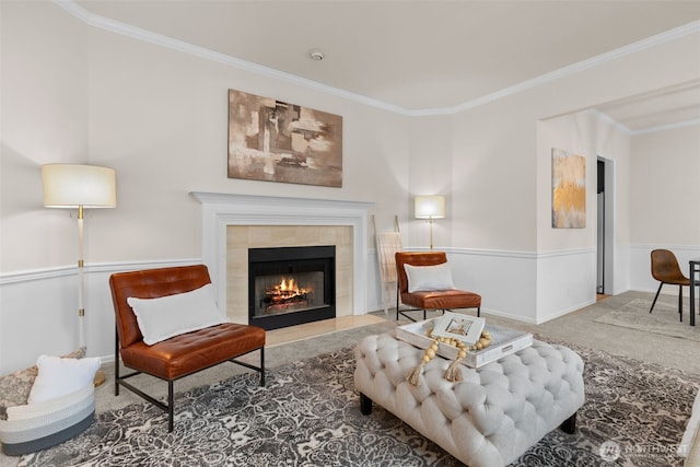 sitting room with a tiled fireplace, crown molding, and carpet flooring