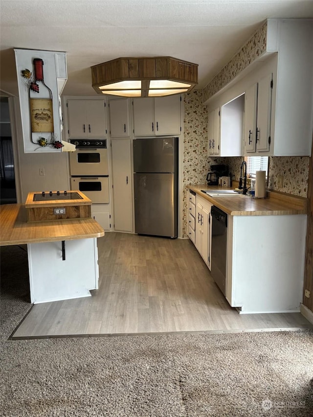 kitchen with sink, stainless steel fridge, white double oven, wooden counters, and black dishwasher