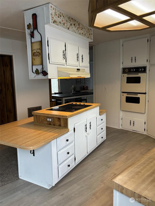 kitchen featuring white cabinetry, black electric cooktop, wood-type flooring, and double oven