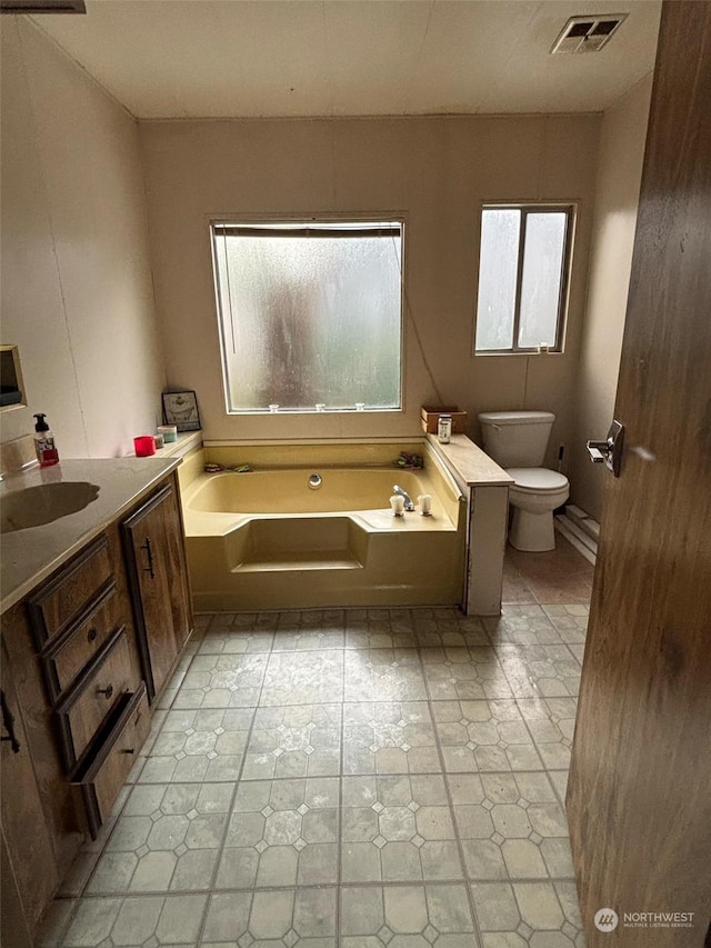 bathroom with a bathing tub, vanity, and toilet