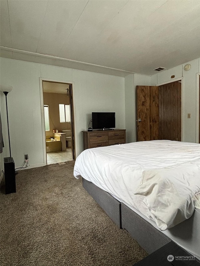 bedroom featuring ensuite bathroom and carpet floors