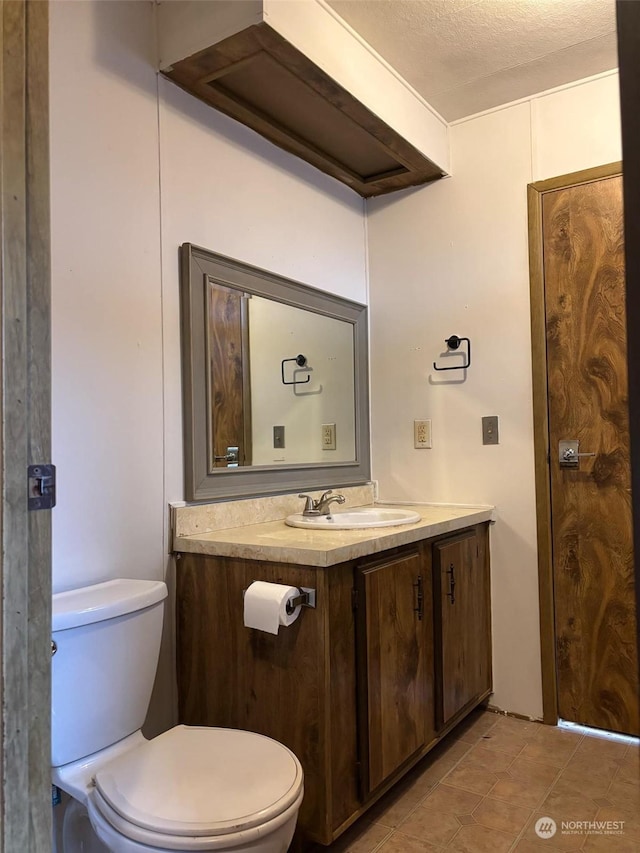 bathroom with vanity, tile patterned flooring, a textured ceiling, and toilet